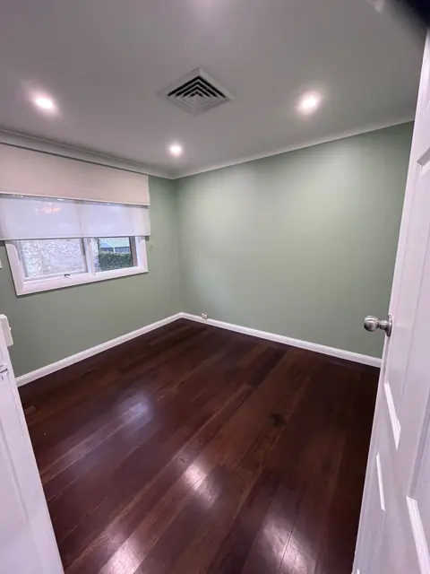 Home office after a makeover, with sage green walls, white trim and timber floor