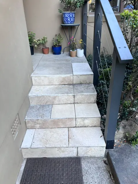 Tiled outdoor stairs with repaired tiles and a newly installed handrail