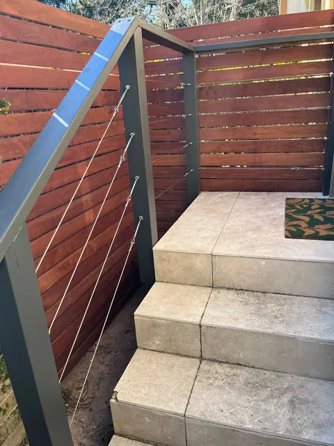 Outdoor stone steps with new horizontal timber screening and a metal handrail